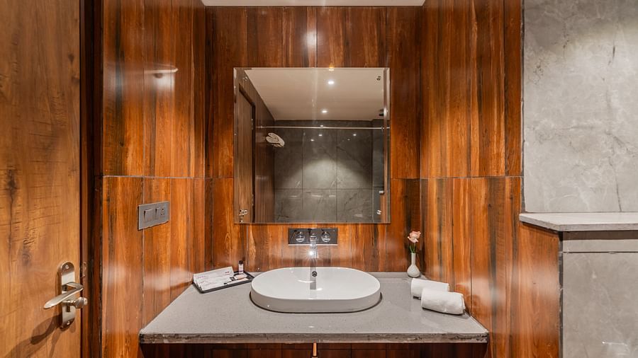 Deluxe King Room bathroom with wooden accents, marble sink, and modern lighting at Clarks Inn Suites Jaipur, Ajmer Road